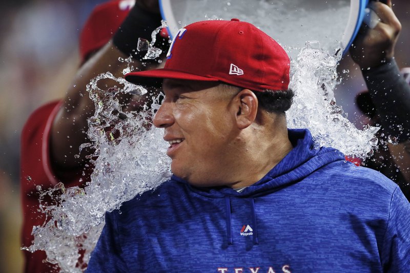 Texas Rangers starting pitcher Bartolo Colon is doused after his 246th career win, the most by a pitcher born in Latin America, after the team's baseball game against the Seattle Mariners, Tuesday, Aug. 7, 2018, in Arlington, Texas. Texas won 11-4. (AP Photo/Brandon Wade)