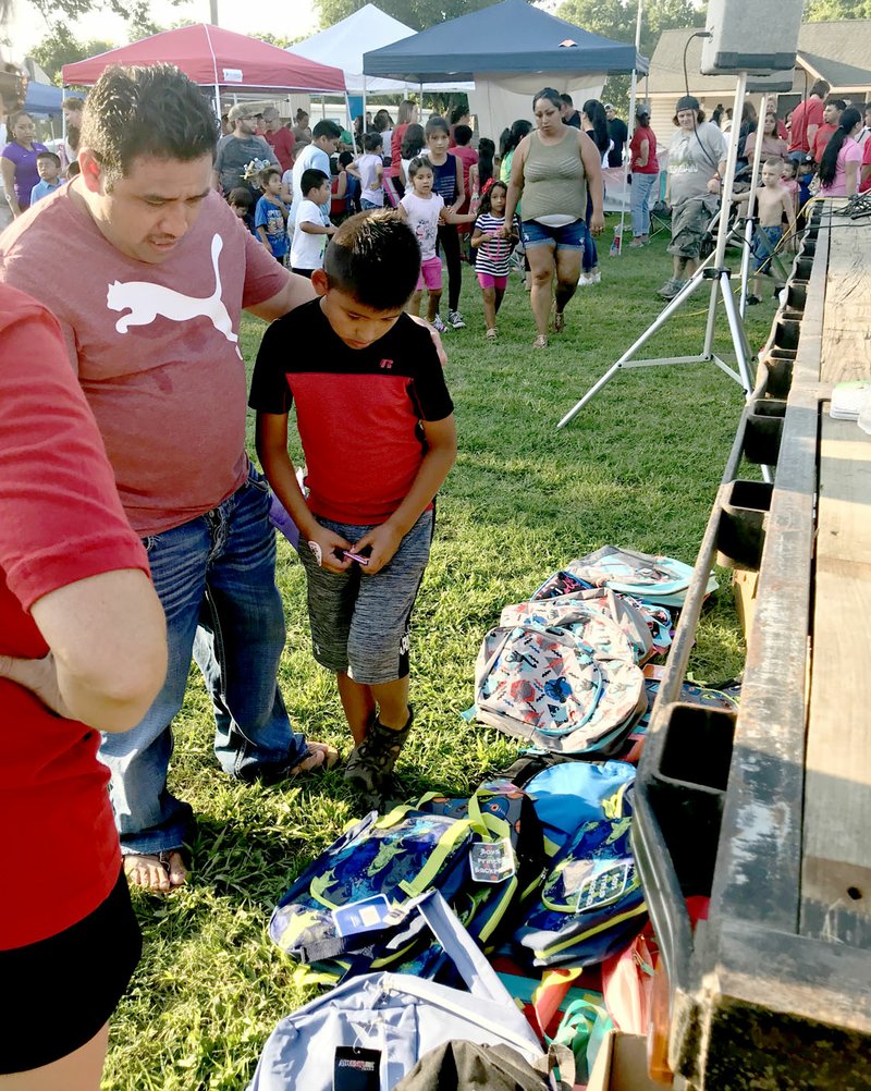 Sally Carroll/McDonald County Press Jose Hernandez-Lopez (left) guides his son, Josque, while he tries to find the perfect backpack. Several lucky winners were able to pick out a backpack at the Noel First Friday/Back-To-School Bash. The Noel Betterment Association teamed up with the Noel Elementary and Primary schools to host the event, which drew a huge crowd to enjoy games, music, a free waterslide, treats and more.