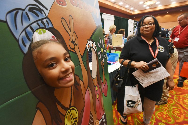 NWA Democrat-Gazette/FLIP PUTTHOFF Aliyah Davis, 11, clowns around Wednesday at a photo booth during opening day of the Association of Arkansas Counties conference at the John Q. Hammons Center in Rogers. Officials from counties around the state opened the conference with vendor exhibits and samples, breakfast and breakout meetings for various posts in county government such as county judges, sheriffs and assessors. The conference continues through Friday. Third District Rep. Steve Womack, R-Rogers, addressed the conference Wednesday. Gov. Asa Hutchinson will speak at 9 a.m. today. Aliyah was at the conference with her grandpa, James Ross of Miller County.