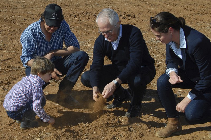In this June 4, 2018, photo, Australian Prime Minister Malcolm Turnbull, second right, looks at dry soil with farmers during a visit to Strathmore Farm near Trangie, 485 kilometers (300 miles) north west of Sydney. Australia's most populous state, New South Wales, was declared entirely in drought on Wednesday, Aug. 8, 2018, and struggling farmers were given new authority to shoot kangaroos that compete with livestock for sparse pasture during the most intense dry spell in more than 50 years. (Ivan McDonnell/AAP Image via AP)