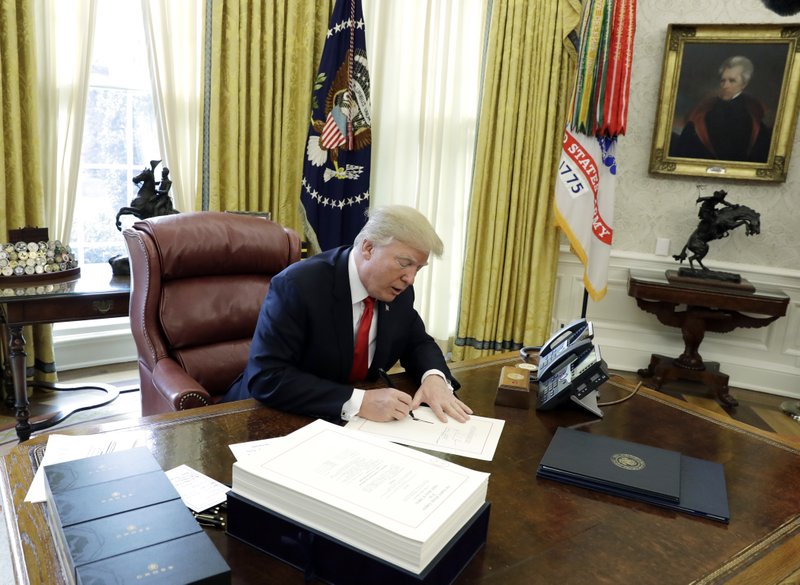 In this December 2017 file photo President Donald Trump signs into law a $1.5 trillion tax overhaul package in the Oval Office of the White House in Washington. New rules floated by the Trump administration lay out what kinds of businesses can take a 20 percent deduction against income taxes under the new tax law. With the proposed rules issued Wednesday, the Treasury Department and the IRS had worked for six months to bring clarity to Congress' blueprint. (AP Photo/Evan Vucci, File)
