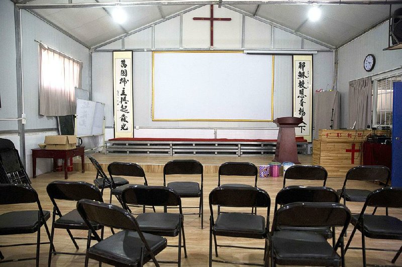 Chinese calligraphy that reads “All nations belong to the Lord arising to shine” at left and “Jesus’s salvation spreads to the whole world” at right are displayed below a crucifix in a house church shut down by authorities near the city of Nanyang in central China’s Henan province.