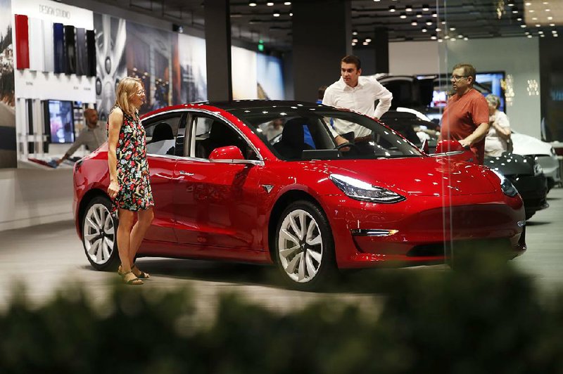 Prospective customers look over a Tesla Model 3 last month at a Denver dealership. Tesla co-founder and CEO Elon Musk tweeted Tuesday that he had “funding secured” to take the company private.  