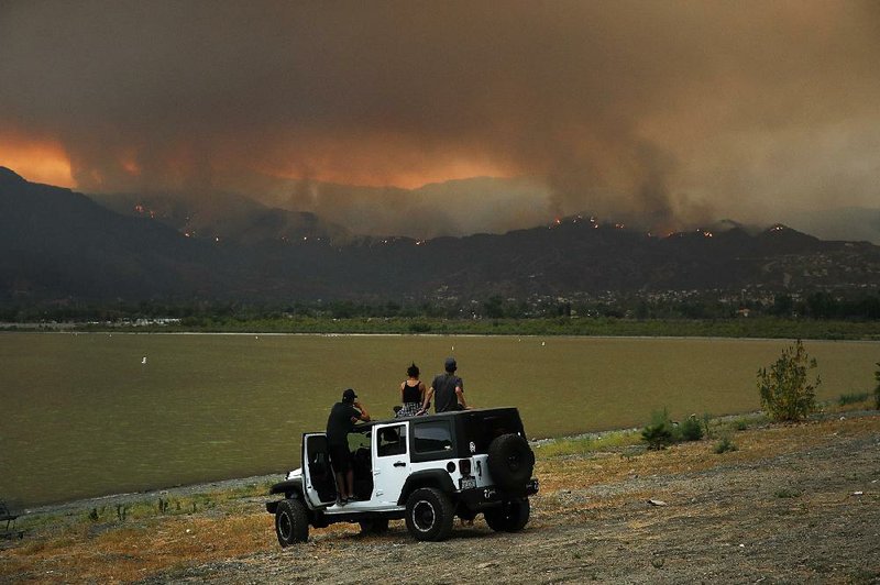 People watch as a wildfire burns Wednedsay near Lake Elsinore, Calif. The federal government is considering whether to allow commercial logging to resume in the Los Padres National Forest north of Los Angeles, a tactic the U.S. Forest Service says will reduce fire risk.