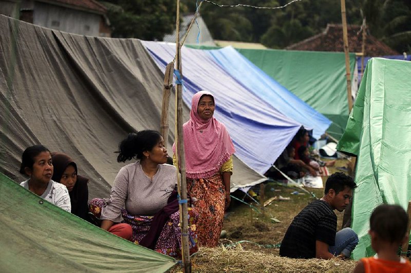 Villagers stand Thursday outside tents at a temporary shelter after being displaced by Sunday’s earthquake in North Lombok, Indonesia.