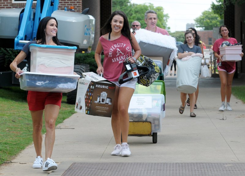 NWA Democrat-Gazette/DAVID GOTTSCHALK Madison Maddox (second from left) walks with her mother Mandy (left) and father John Thursday as they carry items into her dorm room on the first day of Move-in for the 2018-2019 school year on the campus of the University of Arkansas in Fayetteville. University Housing coordinates the effort and staff expect more than 5,200 students to be moving into residence halls during this period.