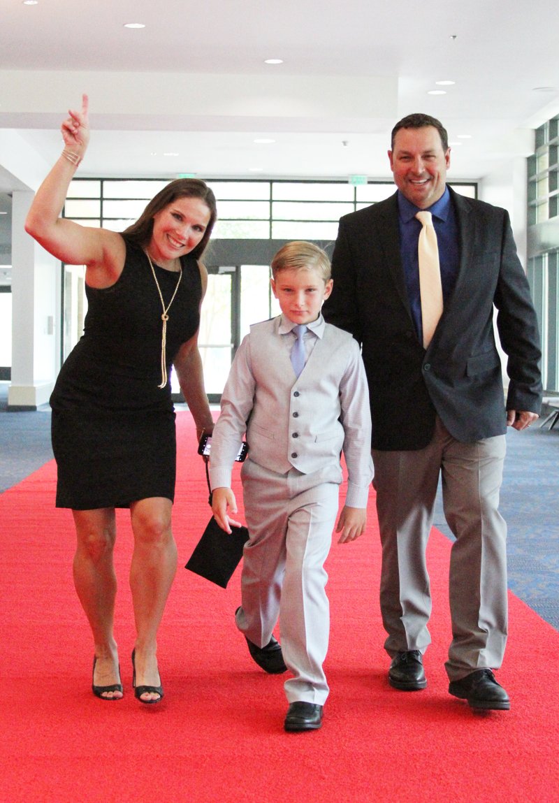 LOOKING UP: Angler Greg Bohannan and his wife Holly and son, Brock, of Bentonville, walk the red carpet Thursday at the Hot Springs Convention Center the night before the Forrest Wood Cup. Bohannan is one of two Arkansans in the hunt for the tournament title, along with top-ranked Mark Rose, of West Memphis.