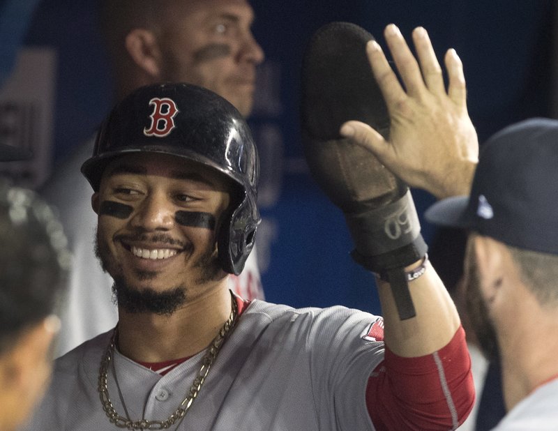 Boston Red Sox's Mookie Betts is congratulated in the dugout after scoring against the Toronto Blue Jays during the first inning of a baseball game Thursday, Aug. 9, 2018, in Toronto. (Fred Thornhill/The Canadian Press via AP)