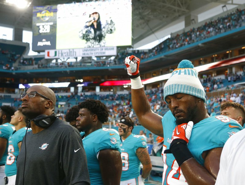 Miami Dolphins defensive end Robert Quinn (94) raises his right fist during the singing of the national anthem, before the team's preseason  game against the Tampa Bay Buccaneers on Thursday, Aug. 9, 2018, in Miami Gardens, Fla. 