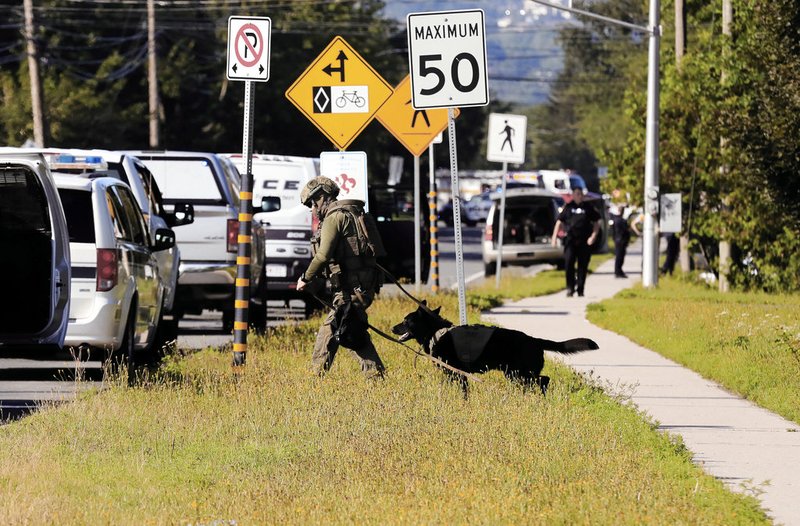 Police officers survey the area of a shooting in Fredericton, New Brunswick, Canada, on Friday, Aug. 10, 2018. 