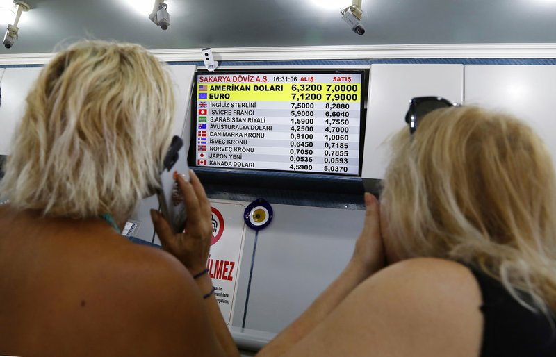 Turkish citizens look at a board showing foreign currency rates inside a currency exchange shop in Ankara, Turkey, on Friday, Aug. 10, 2018. 