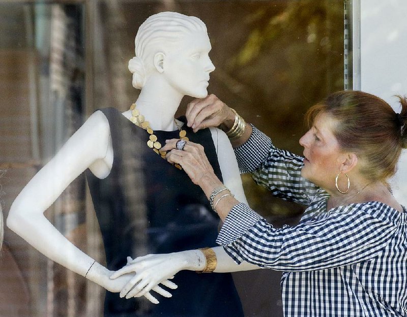 Arkansas Democrat-Gazette/JOHN SYKES JR. -  Feinstein's clothing store sales associate Janie Deveny dresses a mannequin in one of the store's window in Little Rock's Heights neighborhood in 2018. 