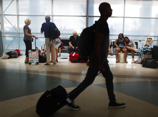 FILE- In this June 29, 2018, file photo, travelers gather on benches to wait for delayed and arriving flights as others make their way to to their gate at the Fort Lauderdale-Hollywood International Airport in Fort Lauderdale, Fla. As summer vacationers start to pack up and head home, Congress is considering a sweeping tally of proposals that could affect travelers, from dictating seat size and legroom to rolling back rules that require airlines to advertise the full price of a ticket. (AP Photo/Brynn Anderson, File)