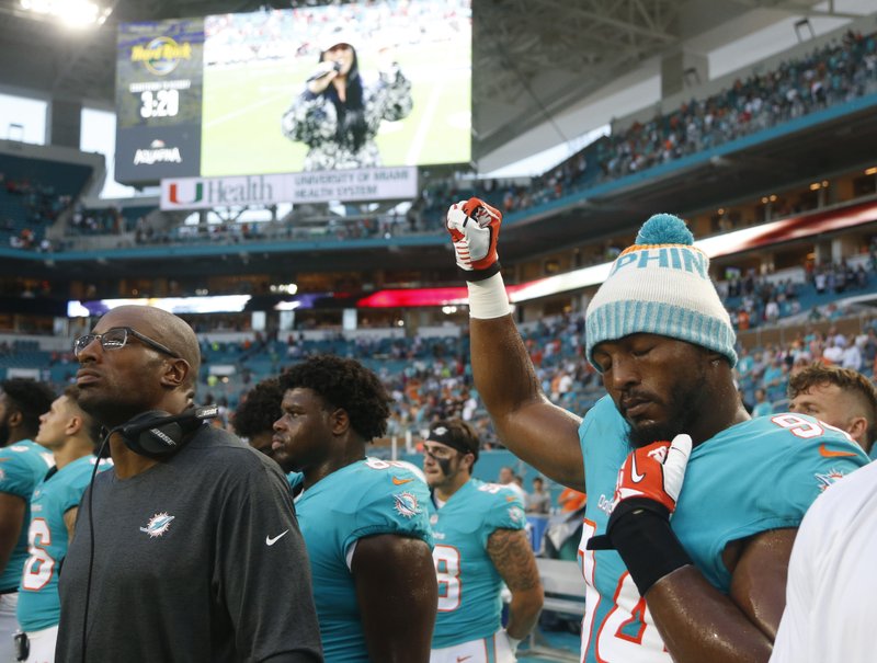 Miami Dolphins defensive end Robert Quinn (94) raises his right fist during the singing of the national anthem, before the team's NFL preseason football game against the Tampa Bay Buccaneers, Thursday, Aug. 9, 2018, in Miami Gardens, Fla. 