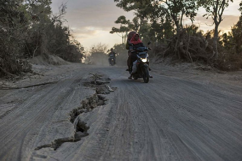 Motorcyclists ride Saturday on a road torn apart by last week’s earthquake in Gangga on the Indonesian island of Lombok. Islanders are still reeling, although some shops have reopened.