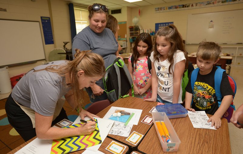  Amy Henderson (left), a second-grade reading teacher at Greenland Elementary School, helps Christina Vaughan (from left) and her children Bella, 8; Ally, 10; and Caiden, 6, Thursday during an open house at the school. Henderson was preparing Vaughan's son Trey for his first day of school. The district starts new teachers with a bachelor's degree at $34,513, one of five Northwest Arkansas school districts that start new teachers at $35,000 or less.