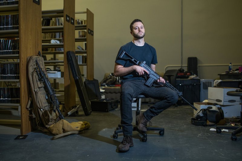 FILE PHOTO: For The Washington Post/TAMIR KALIFA Former Arkansan Cody Wilson holds an assault rifle recently at the library of his Austin nonprofit, Defense Distributed. "Anyone can walk out of my office holding a blueprint. That does not make it a weapon," Wilson says.