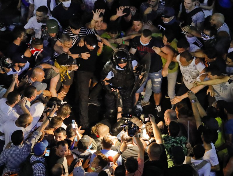 People surround fallen riot police officers during a charge to clear the square during protests outside the government headquarters, in Bucharest, Romania, Friday, Aug. 10, 2018. Romanians who live abroad are staging an anti-government protest calling on the left-wing government to resign and an early election. (AP Photo/Vadim Ghirda)