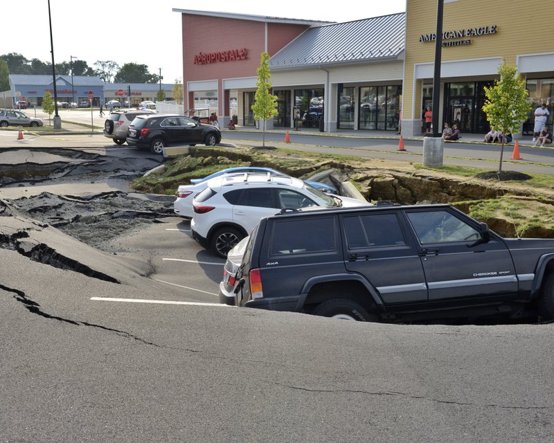 Vehicles sit at the bottom of a sinkhole that opened Friday, Aug. 10, 2018, in a parking lot at Tanger Outlets shopping center in Lancaster, Pa. Six cars were trapped by the sinkhole that opened up in the parking lot of the Pennsylvania outlet mall, but no one was hurt. (Blaine T. Shahan /LNP/LancasterOnline via AP)