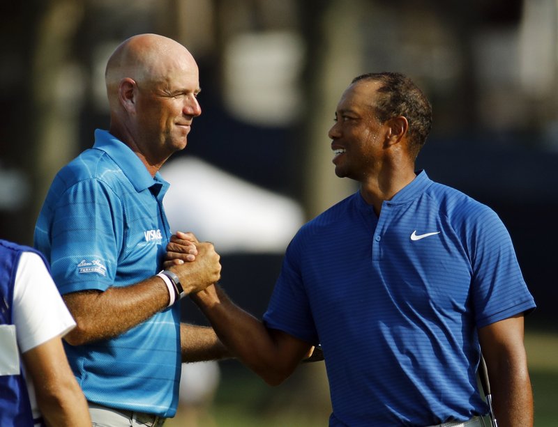 Stewart Cink, left, and Tiger Woods shake hands following the third round of the PGA Championship golf tournament at Bellerive Country Club, Saturday, Aug. 11, 2018, in St. Louis. 