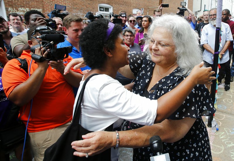 Susan Bro, right, mother of Heather Heyer who was killed during last year's Unite the Right rally, embraces a supporter after laying flowers at the spot her daughter was killed in Charlottesville, Va., Sunday, Aug. 12, 2018. Last year, white supremacists and counterprotesters clashed in the city streets before a car driven into a crowd struck and killed Heyer. 