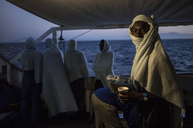 In this photo taken Thursday, Aug. 9, 2018, migrants stand on the deck of the Open Arms boat, after being rescued off the coast of Libya in the early hours of the nigh of Thursday, Aug. 2, 2018. Rescuers from the Spanish non -profit Open Arms saved 87 migrants off the coast of Libya in a dramatic nighttime operation. The group included eight minors. (AP Photo/Valerio Nicolosi)