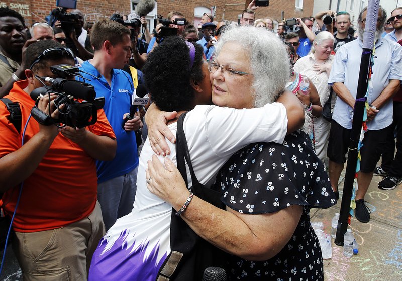 Susan Bro, mother of Heather Heyer who was killed during last year’s Unite the Right rally in Charlottesville, Va., embraces a sup- porter Sunday after laying flowers at the spot where her daughter died. An anti-racism rally in the city drew more than 100 people on the anniversary of last year’s rally. 