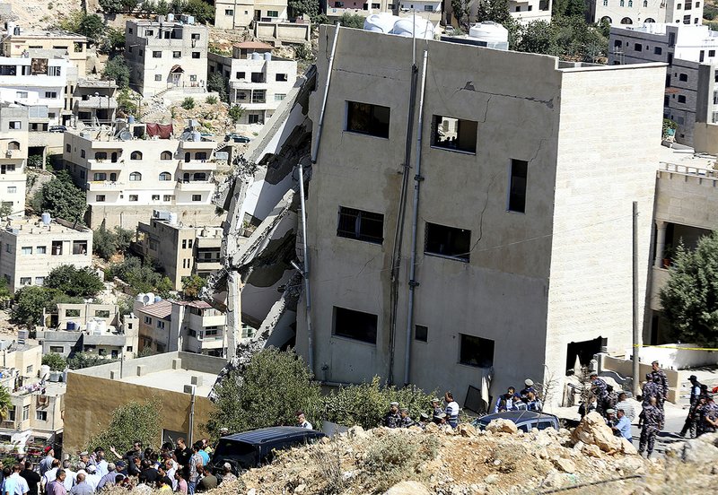 Jordanian security forces inspect the rubble Sunday after the side of a building collapsed when assailants opened fire and set off explosions late Saturday that killed four members of the security forces trying to storm the suspected militant hideout in Salt, west of the capital of Amman. 