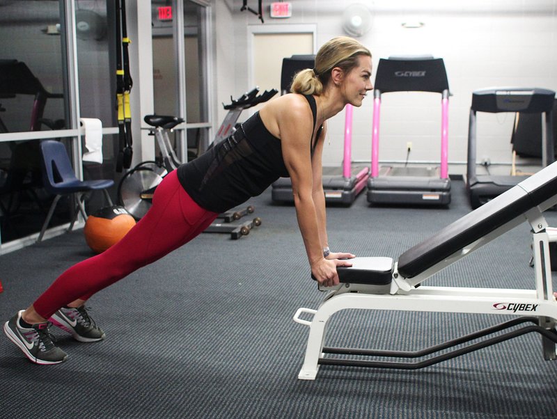 A decline bench would work better, but one wasn’t available when Ashley Bermingham agreed to model the Incline Walking Plank. She uses an incline bench, starting by resting her hands on the pad before inching them upward. Out of sight, a friend stops the bench from rolling. Step 1.