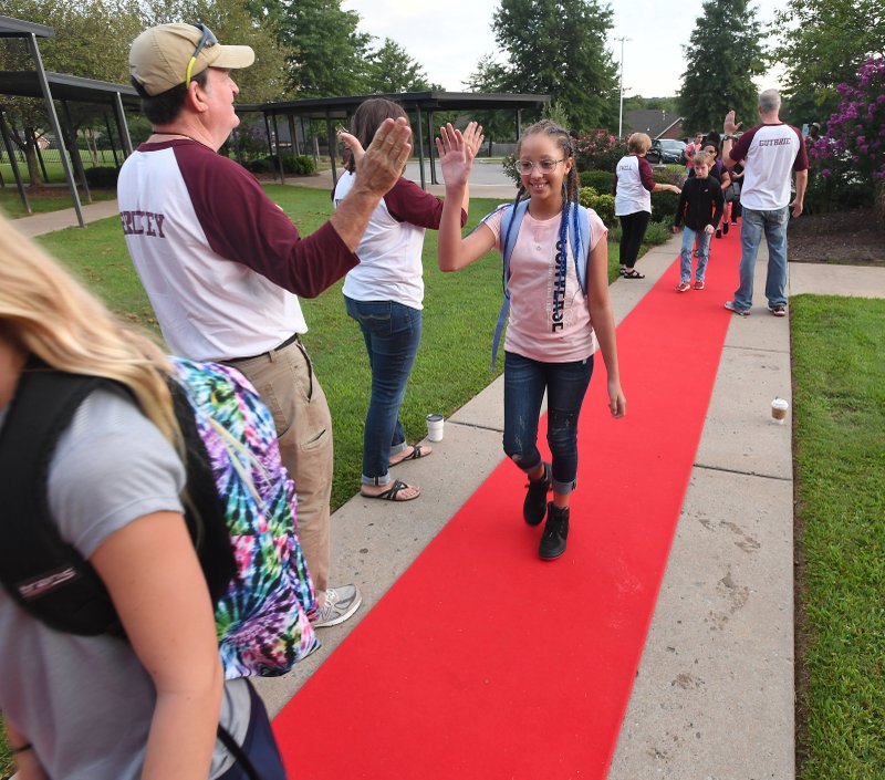 NWA Democrat-Gazette/J.T. WAMPLER Shaina Lane, 10, walks into school Monday at Holt Middle School in Fayetteville. The school has been roiling out a red carpet to welcome students for a few years. Monday was the first day of school for many area schools.
