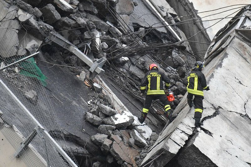 Rescues work among the rubble of the collapsed Morandi highway bridge in Genoa, northern Italy, Tuesday, Aug. 14, 2018. A large section of the bridge collapsed over an industrial area in the Italian city of Genova during a sudden and violent storm, leaving vehicles crushed in rubble below. (Luca Zennaro/ANSA via AP)

