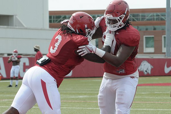 Arkansas defensive linemen Armon Watts (right) and McTelvin Agim go through a drill during practice Wednesday, Aug. 8, 2018, in Fayetteville. 