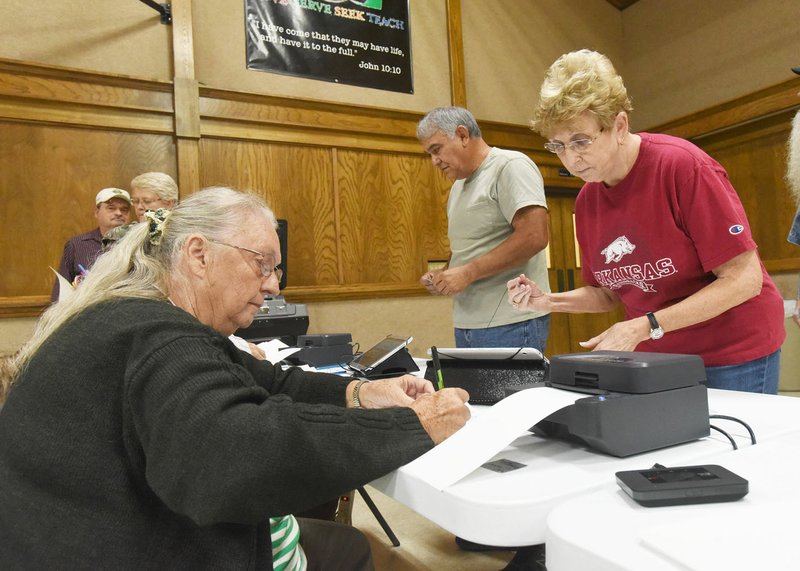 NWA Democrat-Gazette/FLIP PUTTHOFF Poll worker Anna Farar (left) helps Sherry Chacon vote Tuesday in the Rogers bond election.