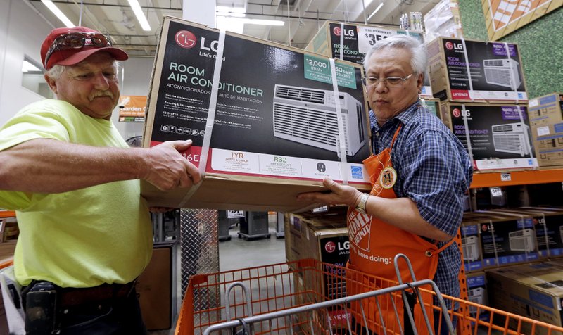 In this Aug. 1, 2017, file photo, store greeter Danny Olivar, right, lends a hand to a customer to heft an air conditioning unit from a rapidly declining stock at a Home Depot store ahead of an expected heat wave in Seattle. The Home Depot Inc. reports earnings Tuesday, Aug. 14, 2018. (AP Photo/Elaine Thompson, File)