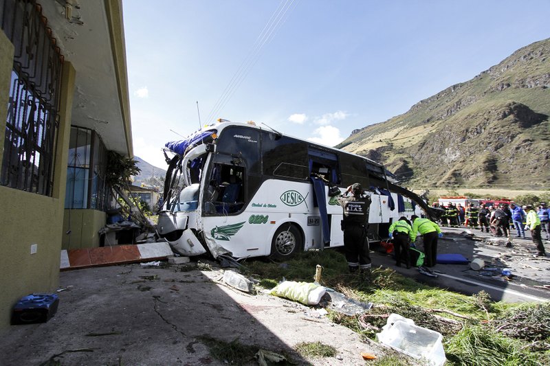 Police and rescue workers work on a Colombian-registered bus traveling to Quito, that crashed in Pifo, Ecuador, Tuesday, Aug. 14, 2018. At least 24 people were killed and another 19 injured when a bus careened into another vehicle at high speed and overturned along the Pifo-Papallacta highway, near Ecuador's capital, local officials reported. (AP Photo/Carlos Noriega)