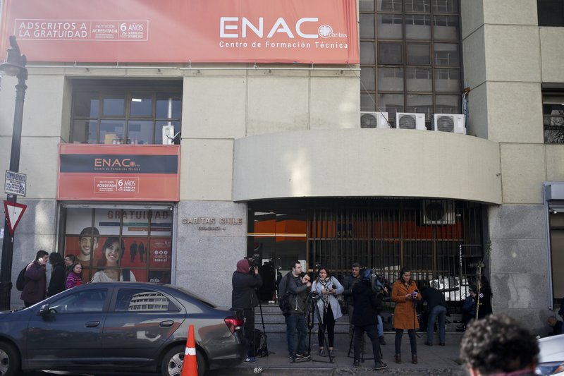 Members of the media wait across the headquarters of the Catholic Church's Episcopal Conference after authorities raided the building in Santiago, Chile, Tuesday, Aug. 14, 2018. Police raided the place as part of a widespread investigation into sex abuse committed by members of the Marist Brothers order in the South American country, prosecutors said. (AP Photo/Esteban Felix)