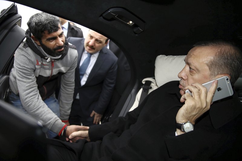 FILE-In this Friday, Dec. 25, 2015 file photo, Turkey's President Recep Tayyip Erdogan, right, holds Turkish citizen Vezir Cakras by the hand while speaking on his mobile phone inside his car stationed over the Bosporus Bridge in Istanbul. Erdogan's office had said he has talked Cakras out of jumping off a bridge to commit suicide. Erdogan said Tuesday, Aug. 18, 2018 that his country will boycott U.S.-made electronic goods amid a diplomatic spat that has helped trigger a Turkish currency crisis. (Yasin Bulbul/Presidential Press Service pool via AP)