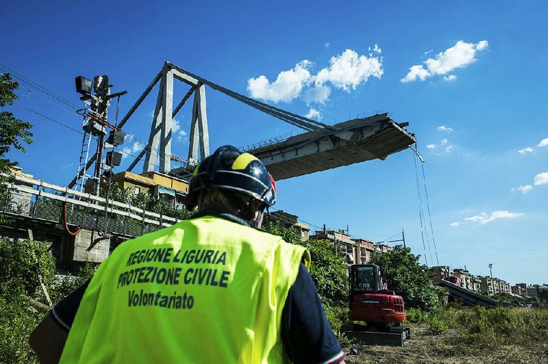 A worker inspects the area Wednesday around the collapsed Morandi highway bridge in Genoa, Italy.  