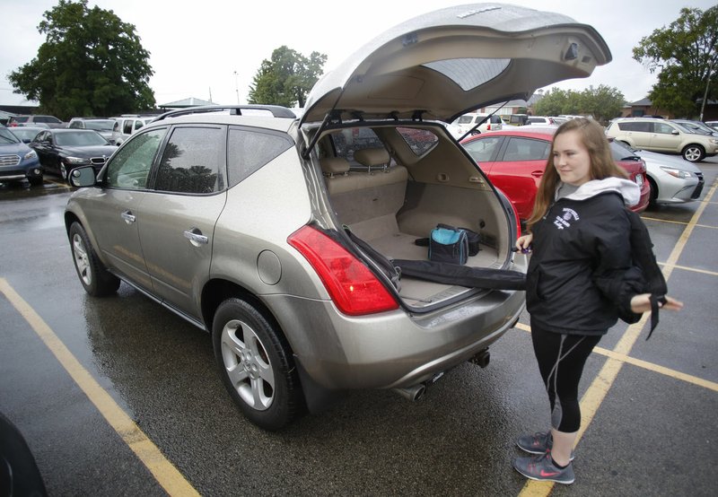 Kaitlyn Mashburn, a senior at Fayetteville High School, picks up her backpack Tuesday after parking her car in the north parking lot at the school. There's a shortage of student parking at the school and for years many nearby residents have allowed/charged students to park on their property. However, three owners have laid down gravel and neighbors have complained to the city, which prompted the city to send out violation notices.