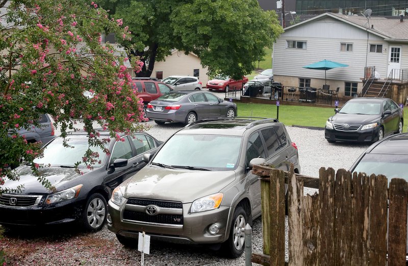 NWA Democrat-Gazette/DAVID GOTTSCHALK Cars are visible parked in marked parking spaces Tuesday in a gravel parking lot on the east side of Buchanan Avenue on the opposite side of Fayetteville High School.