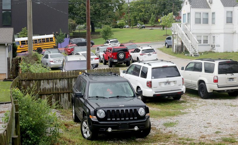 NWA Democrat-Gazette/DAVID GOTTSCHALK Cars are visible parked in marked parking spaces Tuesday in a gravel parking lot on the east side of Buchanan Avenue on the opposite side of Fayetteville High School.