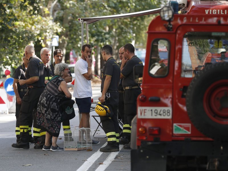 A woman talks to firefighters as they accompany residents to get their belongings from their homes, in Genoa, Italy, Thursday Aug. 16, 2018. Authorities worried about the stability of remaining large sections of a partially collapsed bridge evacuated about 630 people from nearby apartments, some practically in the shadow of the elevated highway. (AP Photo/Antonio Calanni)