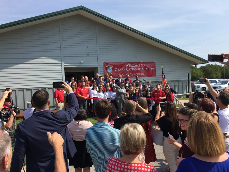 Ozark Catholic Academy students and staff members pose for photos as they participate in the school’s ribbon-cutting ceremony Thursday.
