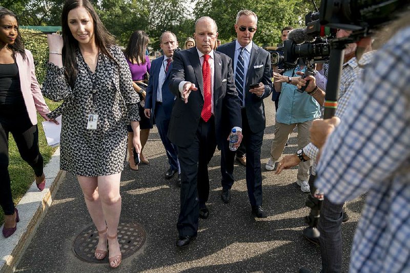White House chief economic adviser Larry Kudlow (center) talks to the media Thursday on the North Lawn of the White House. He said the U.S. and China will resume trade talks later this month in an attempt to defuse geopolitical tensions.  