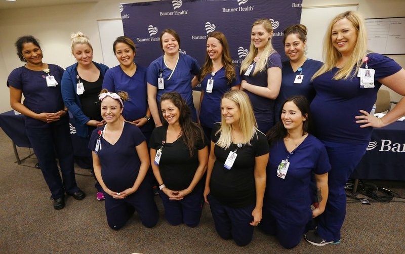 Most of the 16 pregnant nurses who work together in the intensive care unit at Banner Desert Medical Center pose for a group photograph after attending a news conference Friday, Aug. 17, 2018, in Mesa, Ariz.