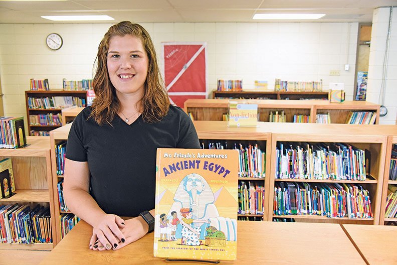 Shelby Tedford, 26, the new Quitman Elementary School media specialist, stands in the library with a book set in Egypt. Tedford said her theme this year is travel, and she wants to take children on journeys through reading.