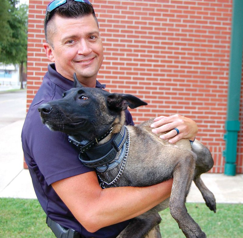 Paul Tarvin, a sergeant with the Bryant Police Department, holds his K-9 partner, Mya, outside the department in Bryant. Tarvin is a school resource officer for the Bryant School District, and Mya has been primarily trained as a narcotics dog, but has also been trained in tracking and article recovery.