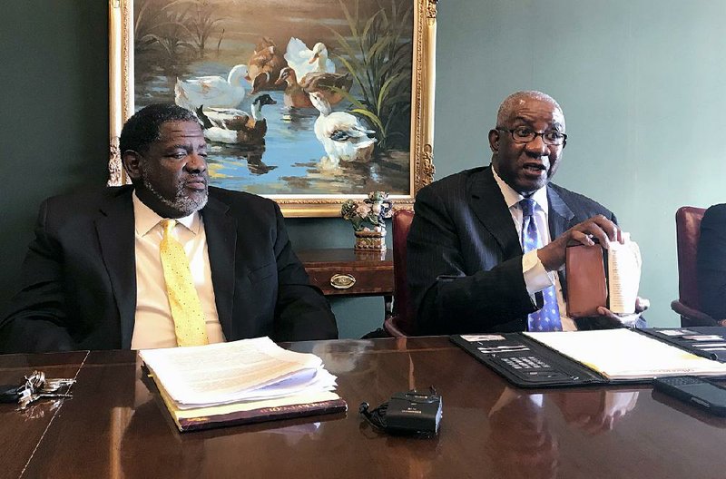 FILE — Pulaski County Circuit Judge Wendell Griffen, right, holds a copy of the U.S. Constitution during a 2018 news conference in Little Rock after a hearing before a judicial ethics panel.