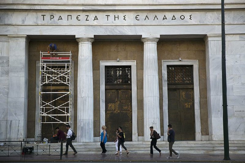 Workers repair the facade of the Athens headquarters of the Bank of Greece in June. As Greece’s bailout nears an end, the country now owes $366 billion in debt, or over 180 percent of its annual economic output.