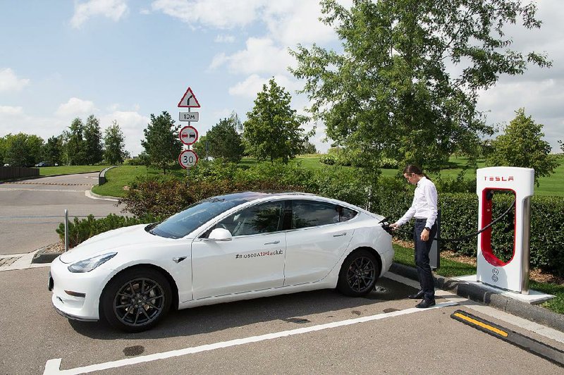 Igor Antarov, managing partner of the Moscow Tesla Club, charg- es a Model 3 last month in Moscow. Tesla stocks tumbled about 9 percent Friday after CEO Elon Musk said in a newspaper inter- view that stress may be getting the better of him.